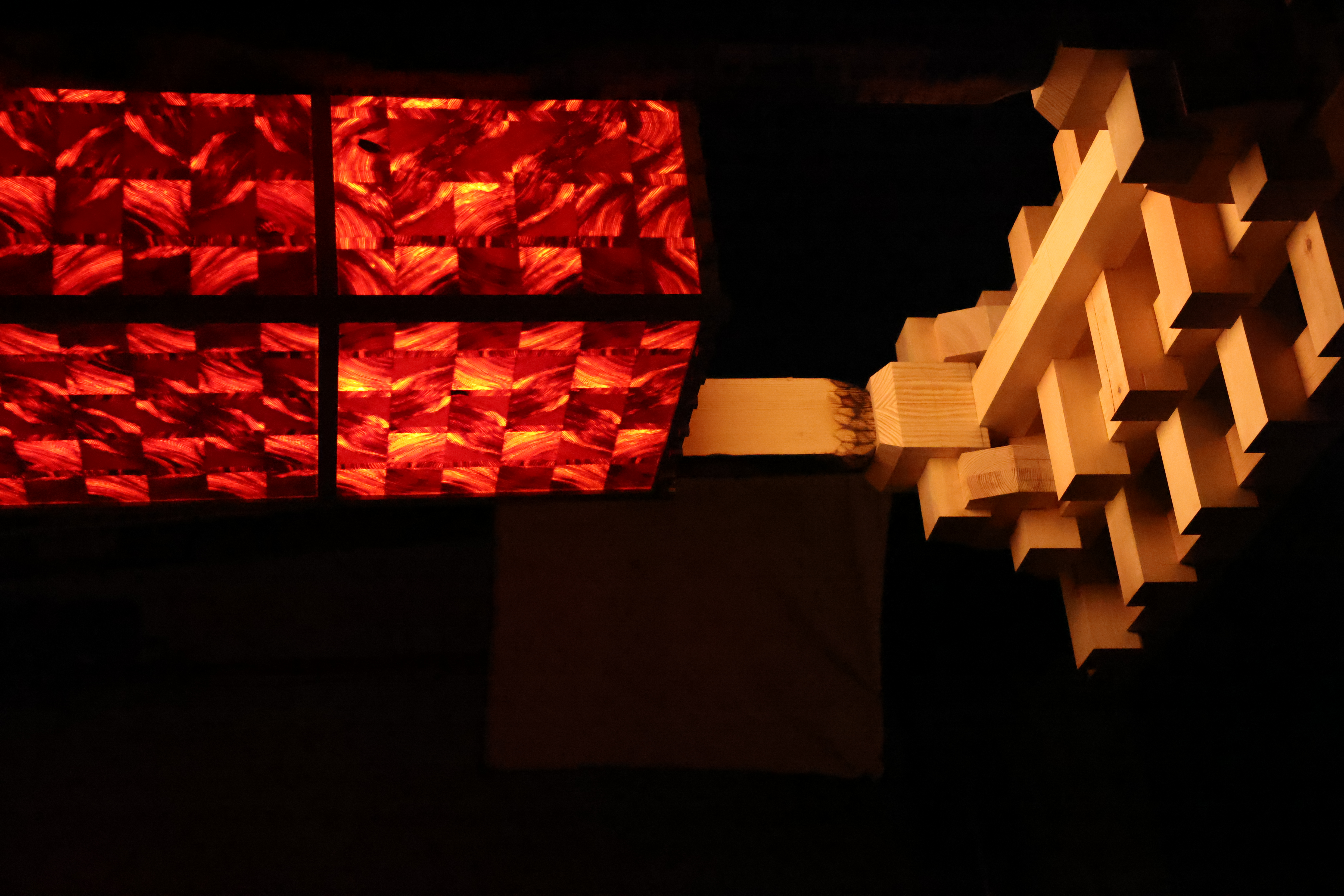 PASSAGE lamp in full — an illuminated red threshold facing its pale timber structure