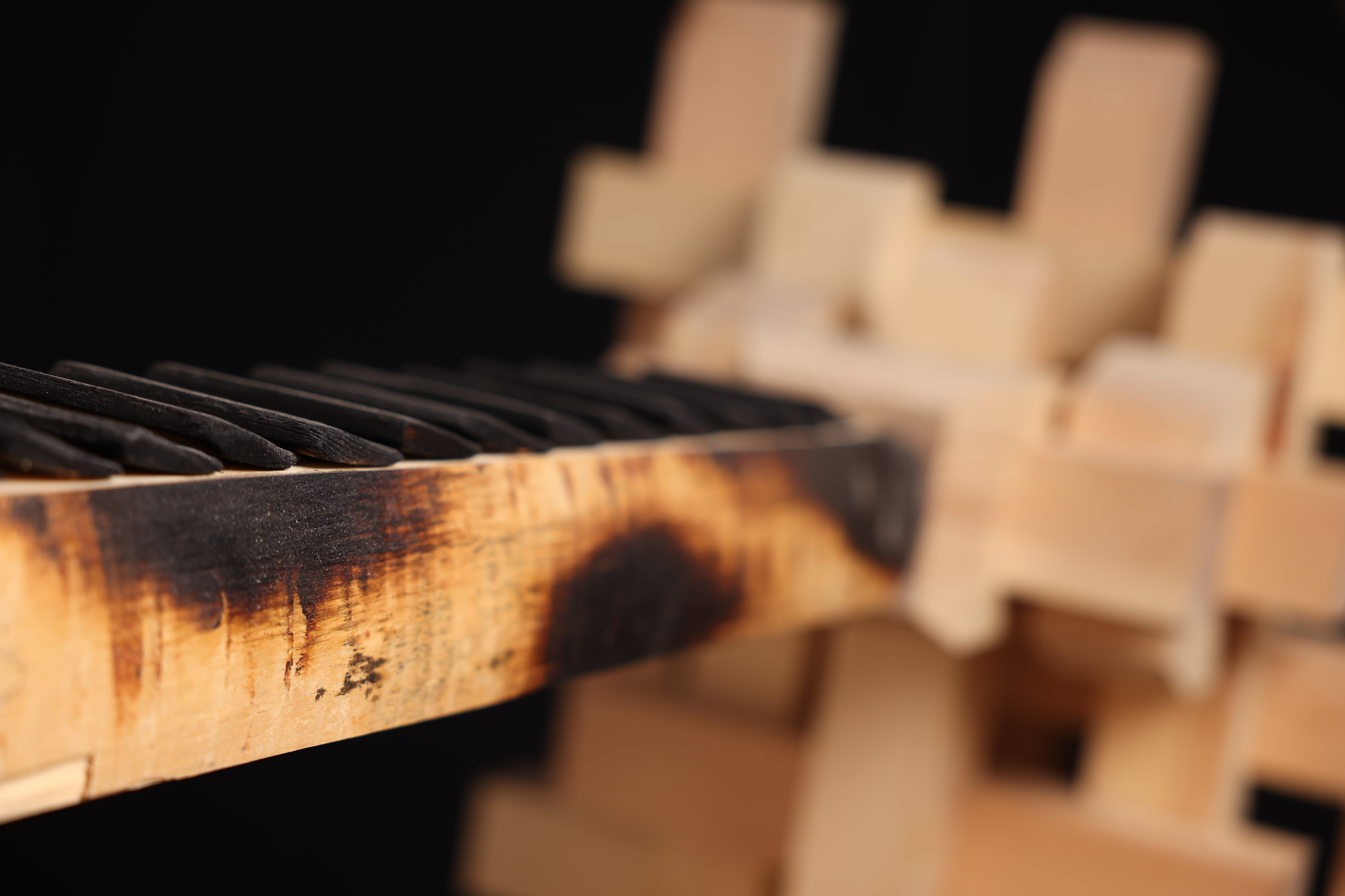 PASSAGE detail — a charred stepped beam extending toward the pale timber assembly