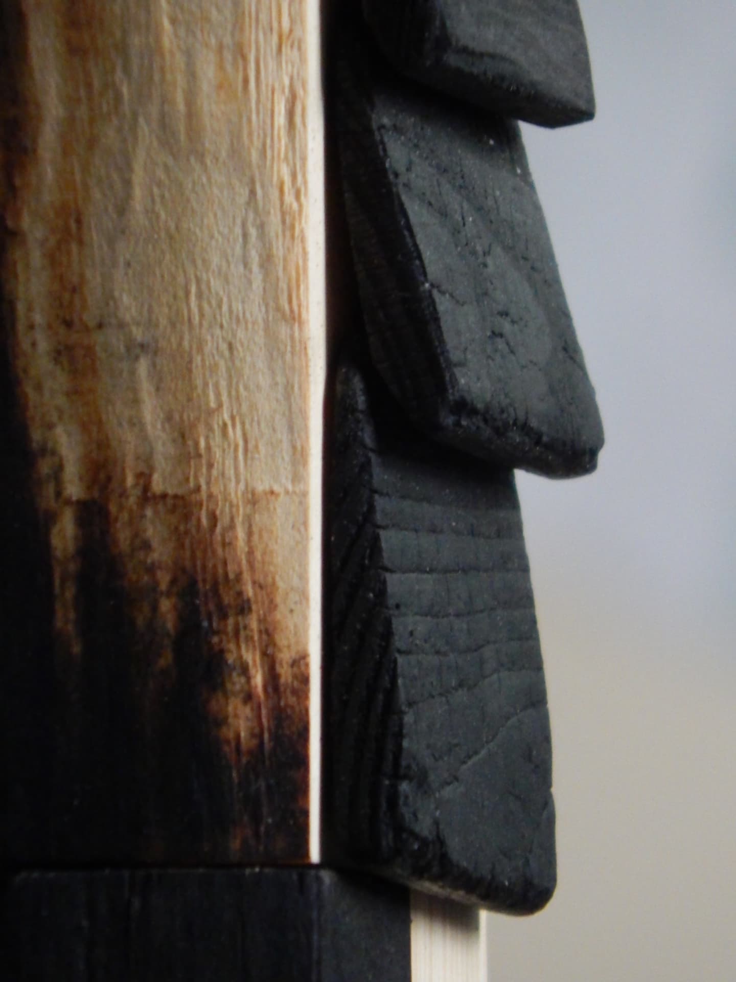 PASSAGE material detail — stepped charred pieces against warm natural wood