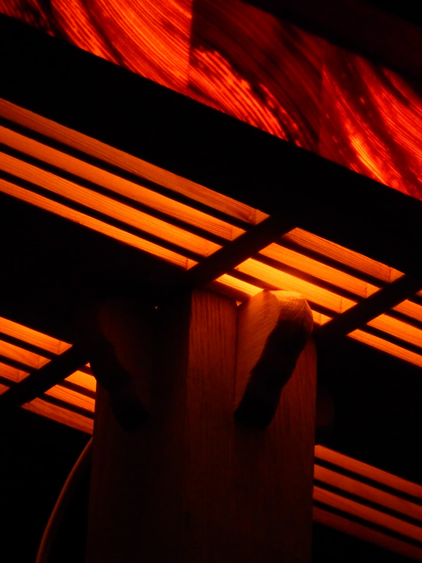 RIFT detail — warm light passing through the wooden lattice above a carved column joint