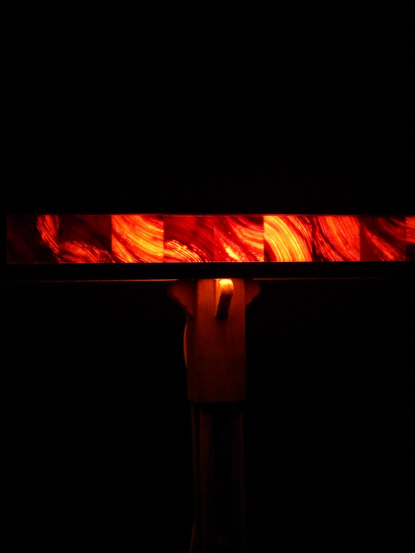 RIFT detail — glowing band of red resin panels held within the dark wooden frame